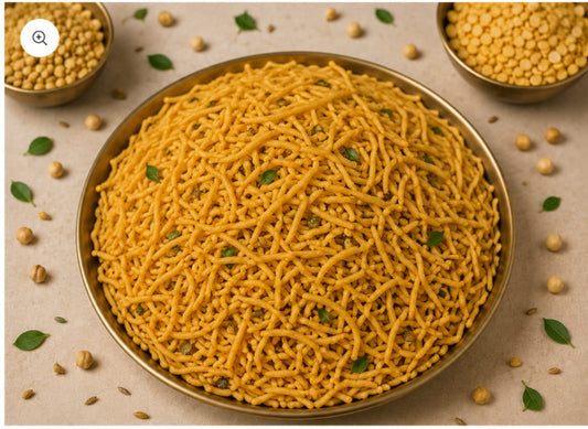 Crispy yellow sev snack mix in a golden bowl with scattered lentils and herbs.